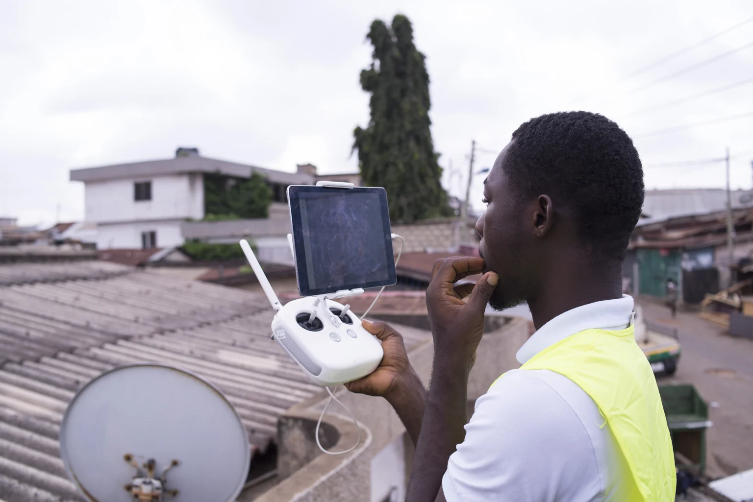 African drone pilot using a controller and tablet to map settlements in Ghana